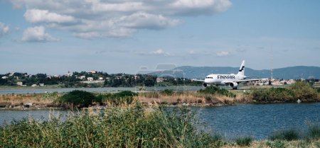 Foto de Kerkyra, Grecia - 09 24 2022: Pintoresco punto turístico Con vistas a la pista del aeropuerto de Corfú, Finnair Avión listo para despegar. Foto de alta calidad - Imagen libre de derechos