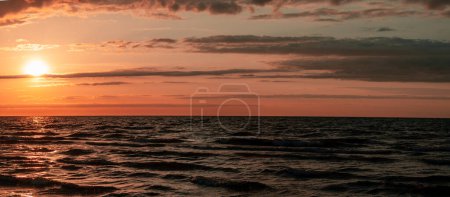 Téléchargez les photos : Panorama avec un coucher de soleil doux inoubliable sur la mer avec des vagues. Le ciel est couvert de nuages. Photo de haute qualité - en image libre de droit