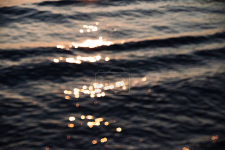 Téléchargez les photos : Cadre flou avec de petites vagues dans lesquelles les rayons du soleil sont réfléchis. Photo de haute qualité - en image libre de droit