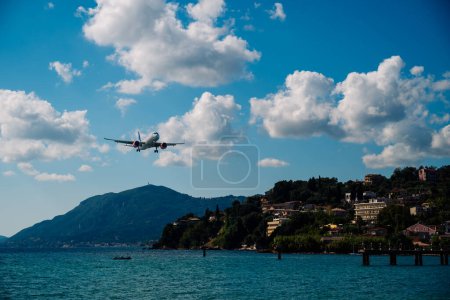 Foto de Kerkyra, Grecia - 09 24 2022: El avión de SAS Scandinavian Airlines aterriza en el aeropuerto de Corfú. En el fondo de la ciudad en las montañas y la pista en el agua. Foto de alta calidad - Imagen libre de derechos