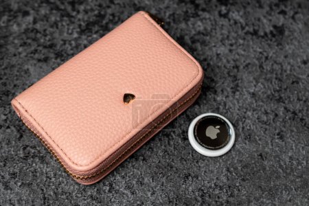 Photo for Jurmala, Latvia - 21 09 2023: On table silver AirTag Apple and pink wallet. Air Tag gadget to track of your stuff and money. High quality photo - Royalty Free Image