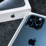 Jurmala, Latvia - 30 11 2023: Close-up box and new smarphone apple iPhone 15 Pro Max in Blue Titanium color on grey table. Focus on camera. High quality photo