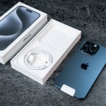 Jurmala, Latvia - 30 11 2023: unboxing of new smarphone apple iPhone 15 Pro Max in Blue Titanium color on grey table. High quality photo