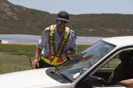 Photo for Western Cape, South Africa, 2023 SAPS South African police officer on a roadside drivers licence and insurance check - Royalty Free Image