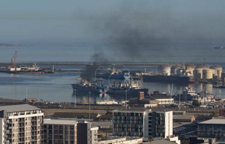 Foto de Port of Cape Town, Sudáfrica. 2023. Humo negro grueso procedente de un buque pesquero situado junto al puerto. - Imagen libre de derechos