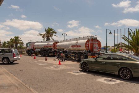 Téléchargez les photos : Langebaan, Western Cape, Afrique du Sud. 2023. Travailleur dirigeant le déchargement de carburant d'un pétrolier et d'une remorque dans un garage à Langebaan, Afrique du Sud - en image libre de droit