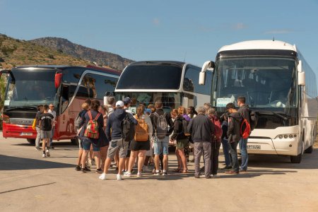 Photo for Elounda, Crete, Greece. 2023. Travellers wait to board their tour bus at the coach station in Elounda a popular coastal resrt in Crete - Royalty Free Image