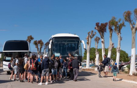 Téléchargez les photos : Elounda, Crète, Grèce. 2023. Les voyageurs attendent pour monter à bord de leur bus touristique à la gare routière d'Elounda un resrt côtier populaire en Crète - en image libre de droit