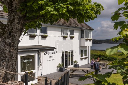 Photo for Isle of Iona, Scotland, UK. 6 June 2023.  The Columba hotel along a country lane with a seaview over the Sound of Iona - Royalty Free Image