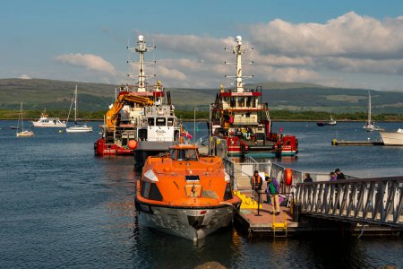 Téléchargez les photos : Tobermory, île de Mull, Écosse, Royaume-Uni. 6 juin 2023. Vue de Tobermory à travers le Sound of Mull sont quelques petits bateaux de loisirs et deux navires de soutien à triple vis. - en image libre de droit