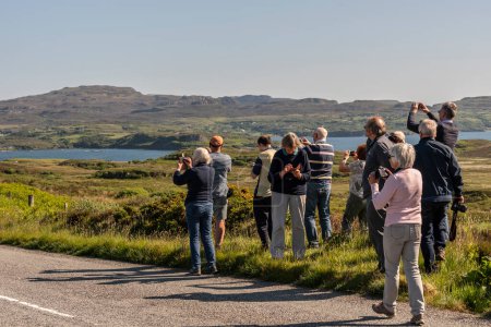 Photo for Ilse of Skye, Scotland, UK.  5 June 2023. Group of coach tour passengers take a break with ther cameras to photograph the scenic countryside on the Isle of Skye. - Royalty Free Image