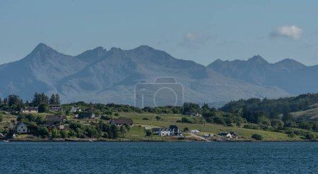 Photo for Isle of Skye, Scotland, UK. 6 June 2023. Panoramic view of the Cuillin mountains across green countryside and residential homes on the Isle of Skye. - Royalty Free Image