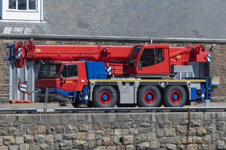 Foto de Puerto de St Peters, Guernsey, Islas del Canal. 11 junio 2023. Una grúa todo terreno pintada de rojo y azul en el muelle del puerto de San Pedro. - Imagen libre de derechos