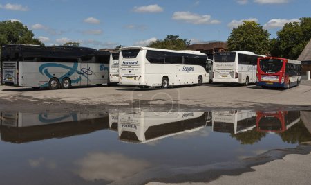 Photo for Salisbury, Wiltshire, England, UK. 9 August 2023. Bus and coaches parked close to a large puddle of rainwater, concept of English weather. - Royalty Free Image