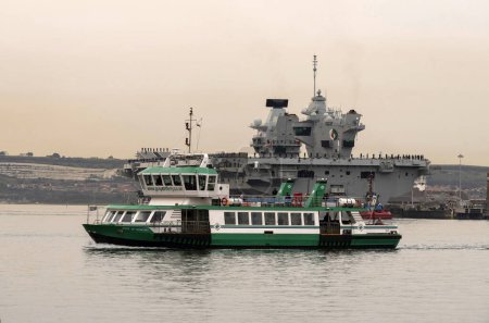 Foto de Portsmouth, Inglaterra, Reino Unido. 8 de septiembre de 2023. HMS Queen Elizabeth girando con la ayuda de remolcadores antes de salir del astillero de Portsmouth al atardecer en el despliegue de operaciones militares. - Imagen libre de derechos