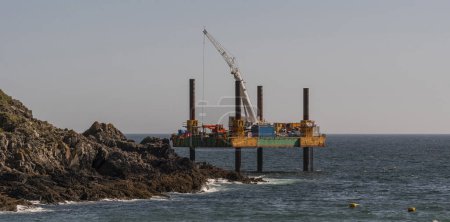 Photo for Polperro, Cornwall, England, UK.  4th September 2023.  Remedial work being carried out from a jack up platform in the sea to cover with concrete an outfall pipe in Polperro, Cornwall, UK. - Royalty Free Image