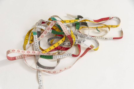 Photo for Studio shot of a selection of tape measures in a tangle on a white backdrop. - Royalty Free Image