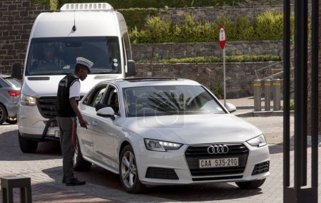 Photo for Cape Town South Africa. 18/03/2024.  Security guard taking to a car driver in the waterfront area in Cape Town,, South. Africa. - Royalty Free Image