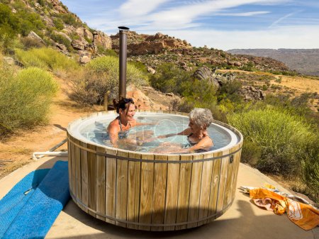 Photo for Vleiplaas Clanwilliam Cederberg South Africa. 14/02/2024. Women campers enjoying the wood fired hot tub in the open air. - Royalty Free Image