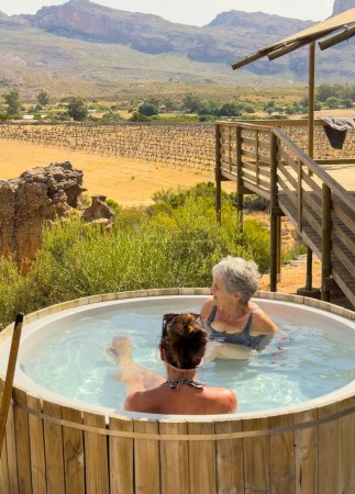 Photo for Vleiplaas Clanwilliam Cederberg South Africa. 14/02/2024. Women campers enjoying the wood fired hot tub in the open air. - Royalty Free Image