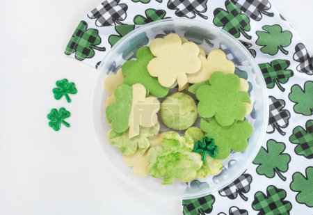 Photo for Unfrosted Shamrock Sugar Cookies in Container with Shamrock Towel - Royalty Free Image