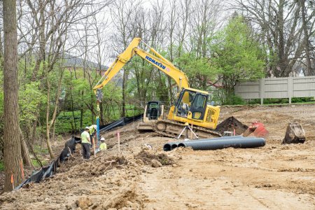Photo for Dayton, Ohio - April 9, 2024: Construction workers installing concrete block as part of housing construction development drainage system. - Royalty Free Image