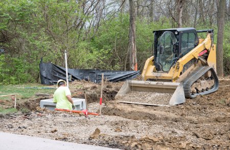 Photo for Dayton, Ohio - April 9, 2024: Construction worker stands in drainage trench while working on corner catch basin as part of housing development drainage system. - Royalty Free Image