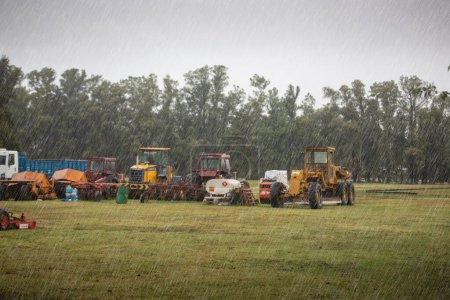 Téléchargez les photos : Tractors on field in rainy day - en image libre de droit