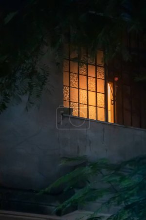 Téléchargez les photos : Fenêtre de la maison avec lumière dans la nuit - en image libre de droit