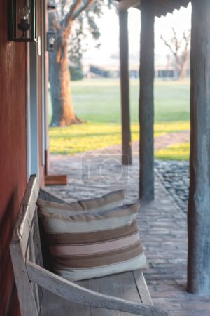 Téléchargez les photos : Un banc avec des oreillers assis sur un patio en brique - en image libre de droit