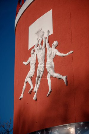 Téléchargez les photos : Sculptures d'athlètes masculins sur le mur rouge - en image libre de droit