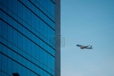 Téléchargez les photos : Avion volant près d'un bâtiment moderne dans la ville - en image libre de droit