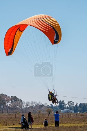 Téléchargez les photos : Un couple volant en parachute dans un champ - en image libre de droit