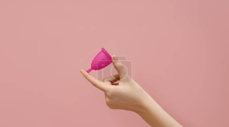 Photo for Female hand holding menstrual cup on pink background, woman wellbeing concept - Royalty Free Image