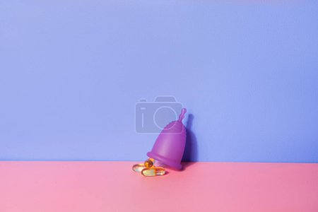 Photo for Female menstual cup and oil capsules on pink table. Woman well-being concept - Royalty Free Image