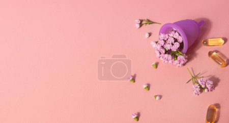 Photo for Female menstual cup, flowers and oil capsules on pink table. Woman well-being concept - Royalty Free Image