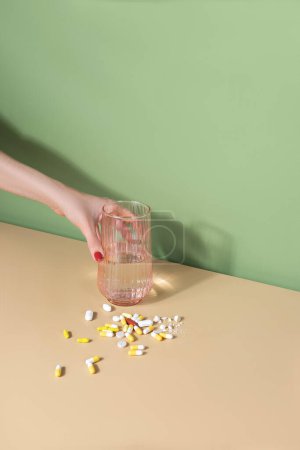 Photo for Female hand putting a glass of water. handful of pills on a table. Well-being concept - Royalty Free Image