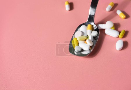 Photo for Colourful pills in a spoon on a pink table. Well-beign or medicine concept - Royalty Free Image