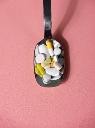 Photo for Colourful pills in a spoon on a pink table. Well-beign or medicine concept - Royalty Free Image