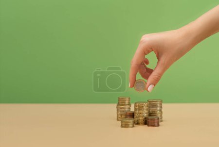 Photo for Female hand holding a coin above the stack of coins. Finance concept - Royalty Free Image