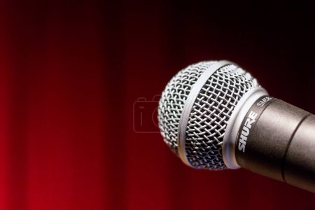 Téléchargez les photos : Un gros plan d'un microphone shure contre le rideau de scène rouge finnegans - en image libre de droit