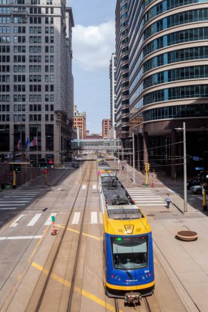Téléchargez les photos : MINNEAPOLIS, MN - MARS 2019 - Prise de vue grand angle orientée portrait d'un train de ligne verte se dirigeant vers le centre-ville de Minneapolis un jour de travail vu du skyway. - en image libre de droit