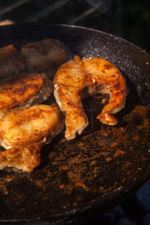 Téléchargez les photos : Poêle avec steak de poisson à frire sur le feu. Cuisine extérieure. Barbecue d'été et vacances - en image libre de droit
