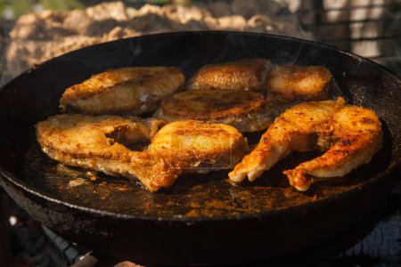 Poêle avec steak de poisson à frire sur le feu. Cuisine extérieure. Barbecue d'été et vacances