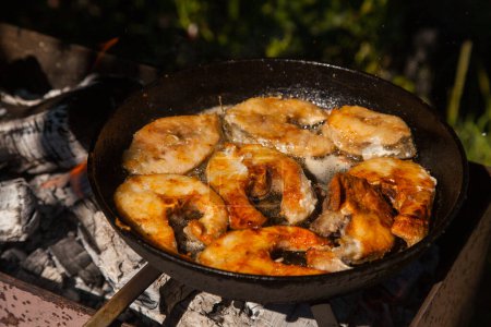 Pan with frying fish steak on the fire. Outdoor kitchen. Summer barbeque and vacation