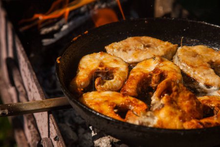 Sartén con filete de pescado frito en el fuego. Cocina exterior. Barbacoa de verano y vacaciones