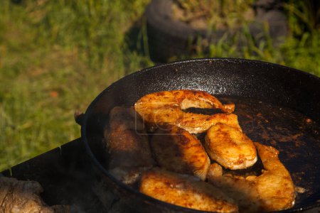 Pfanne mit frittiertem Fischsteak auf dem Feuer. Outdoor-Küche. Sommergrillen und Urlaub