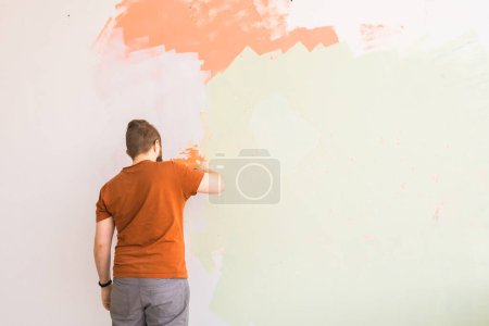 Photo for Young man using spatula and plastering of wall with white fresh finishing putty. Closeup. Repair work of home. Empty place for text. Side view - Royalty Free Image