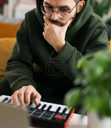 Photo for Recording electronic music track with portable midi keyboard on laptop computer in home studio. Producing and mixing music, beat making and arranging audio content with professional audio devices - Royalty Free Image