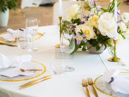 Foto de Boda. Banquete. Las sillas y la mesa redonda para los huéspedes, servidas con cubiertos, flores y vajilla y cubiertas con un mantel - Imagen libre de derechos